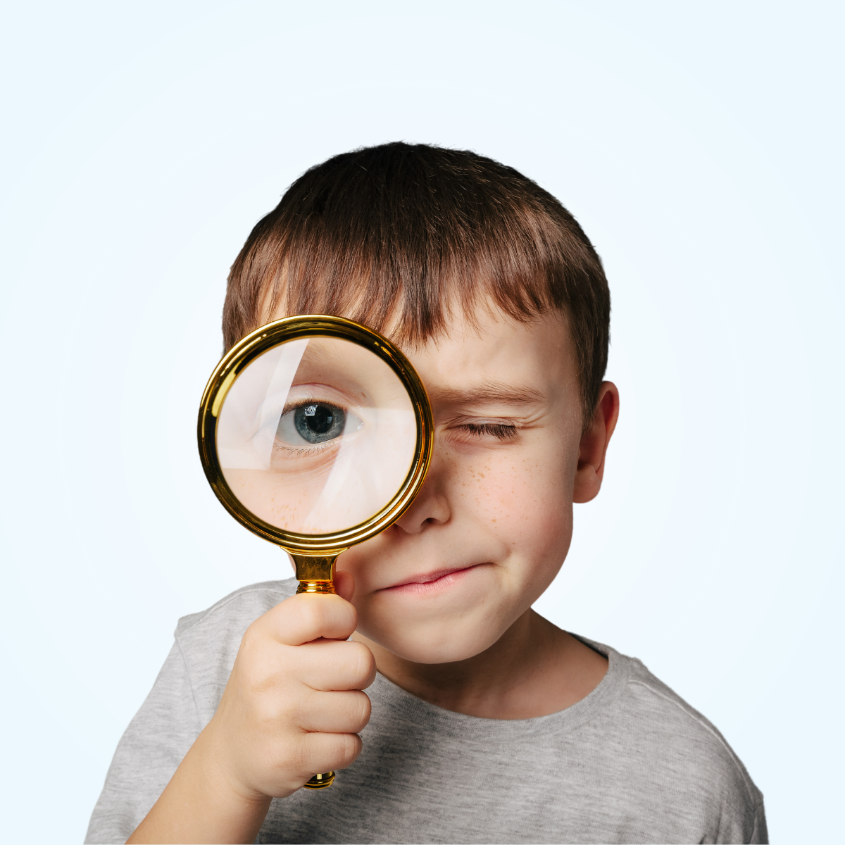 child holding magnifying glass up to eye