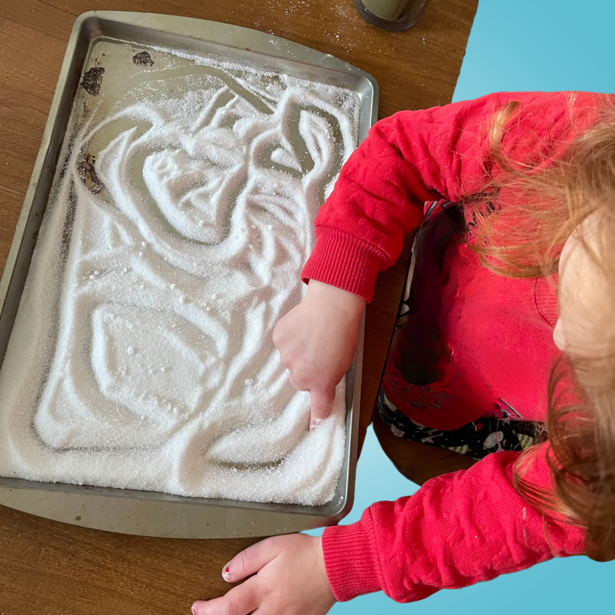 student writing in sand with finger