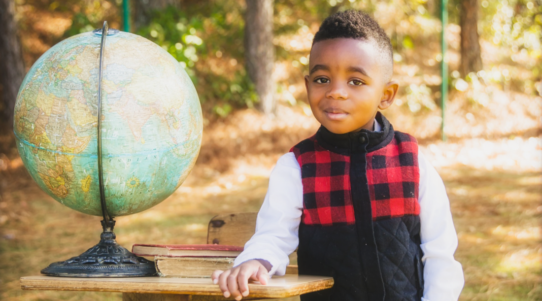 boy standing at desk with globe