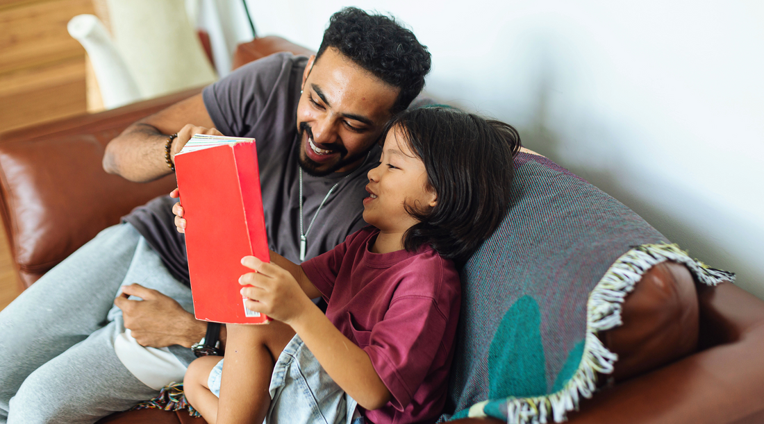 A girl and man sitting, reading a book