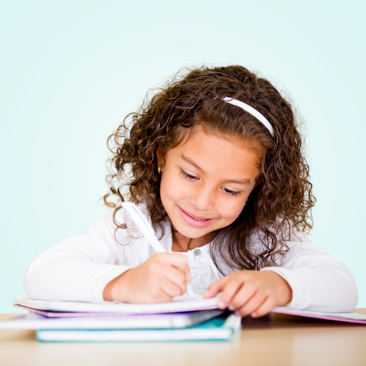 child smiling and writing in notebook